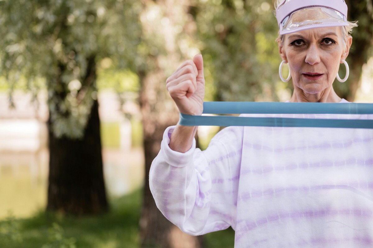 Starija ženska osoba vježba uz pomoć elastiče trake.